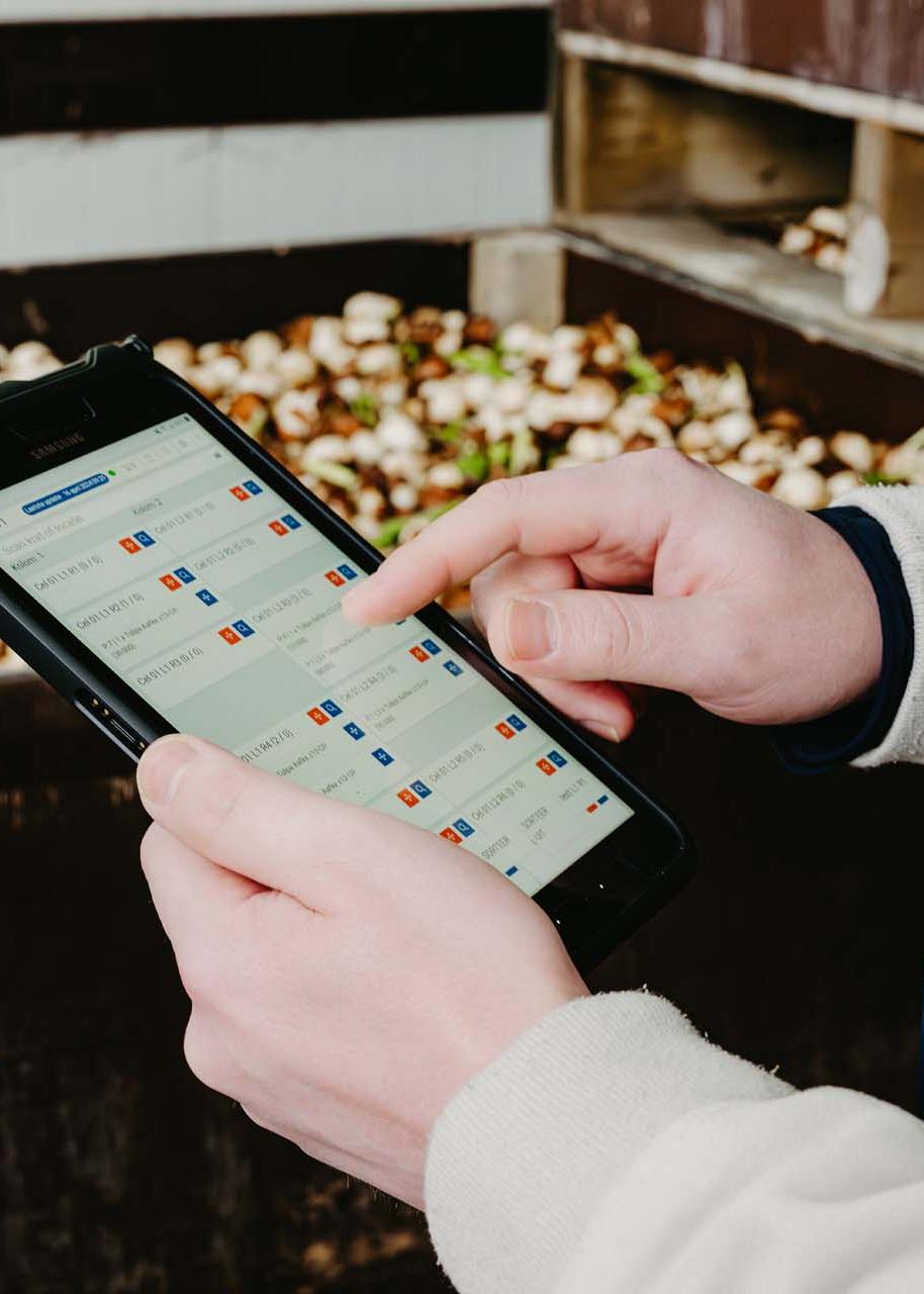 Handen die een tablet vasthouden waarop gegevens worden getoond.