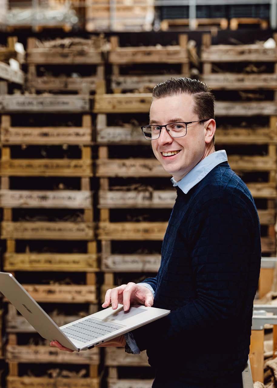 Smart Bulb consultant met laptop in handen voor kratten met bollen.