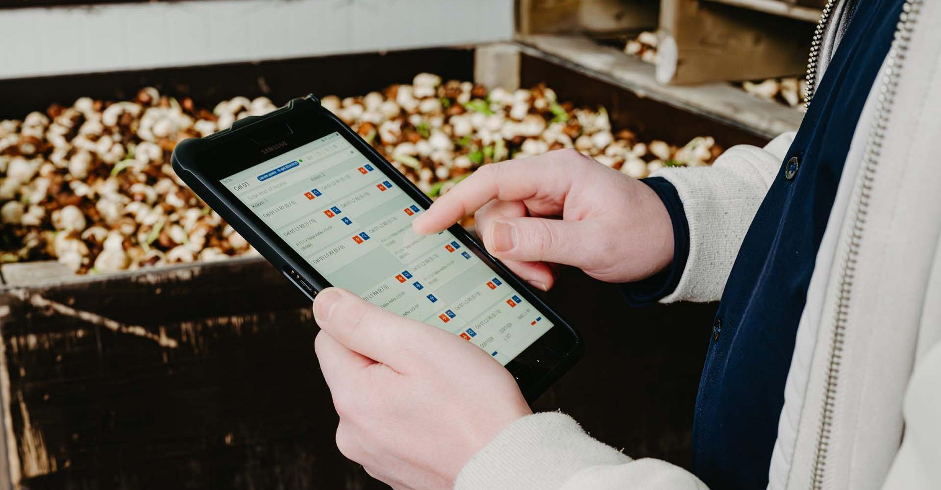 Handen die een tablet vasthouden waarop gegevens worden getoond.