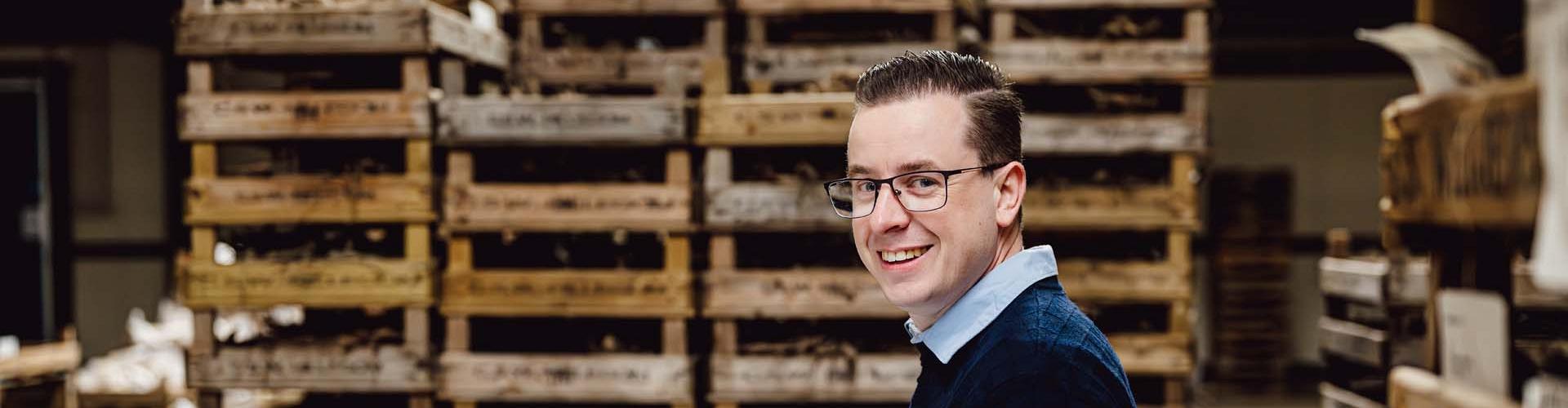 Smart Bulb consultant met laptop in handen voor kratten met bollen.