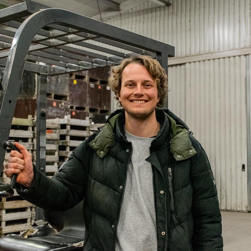 Een man inspecteert bloembollen in een opslagruimte vol houten kratten.
