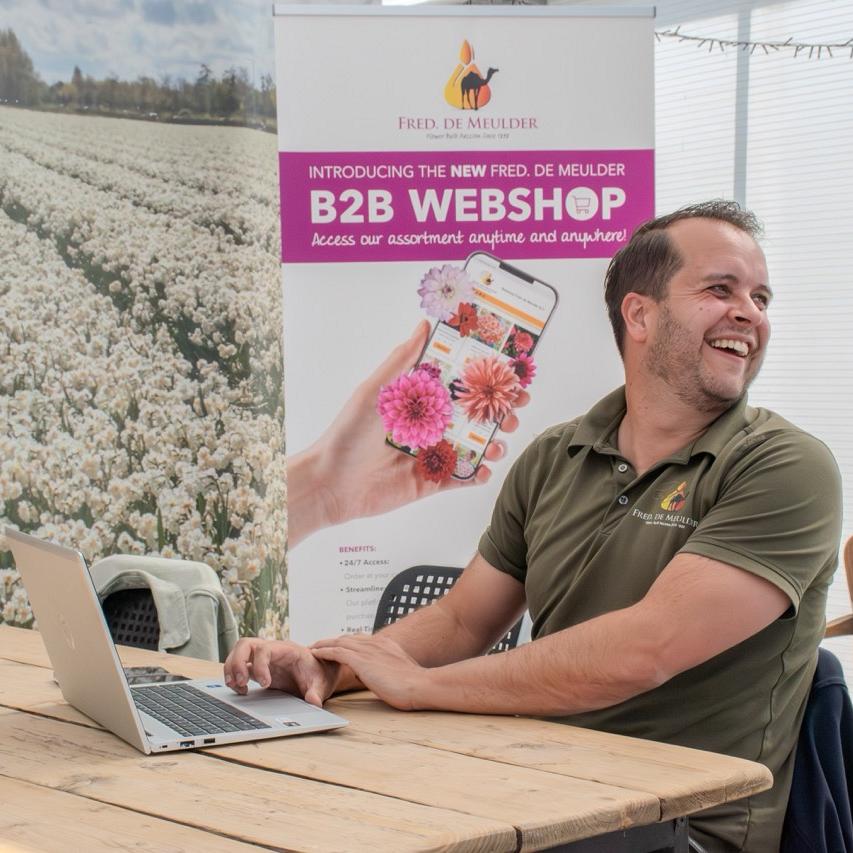 Man aan tafel met laptop voor banner van Fred. de Meulder B2B-webshop in kasomgeving.