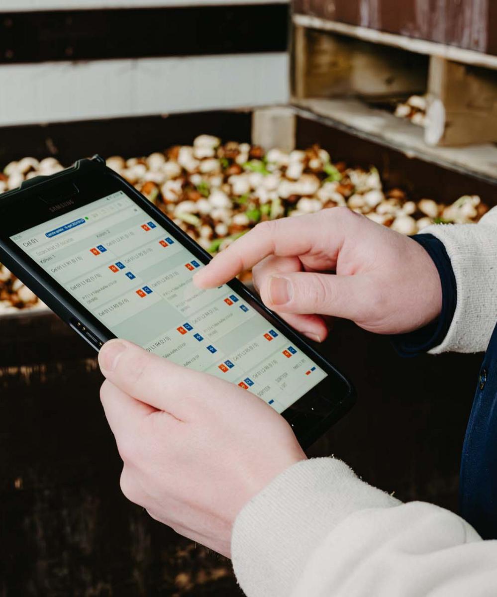 Handen die een tablet vasthouden waarop gegevens worden getoond.