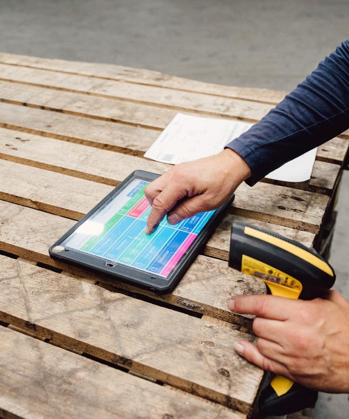Persoon tikt op tablet met daarop Smart Bulb software met in zijn andere hand een scanner.