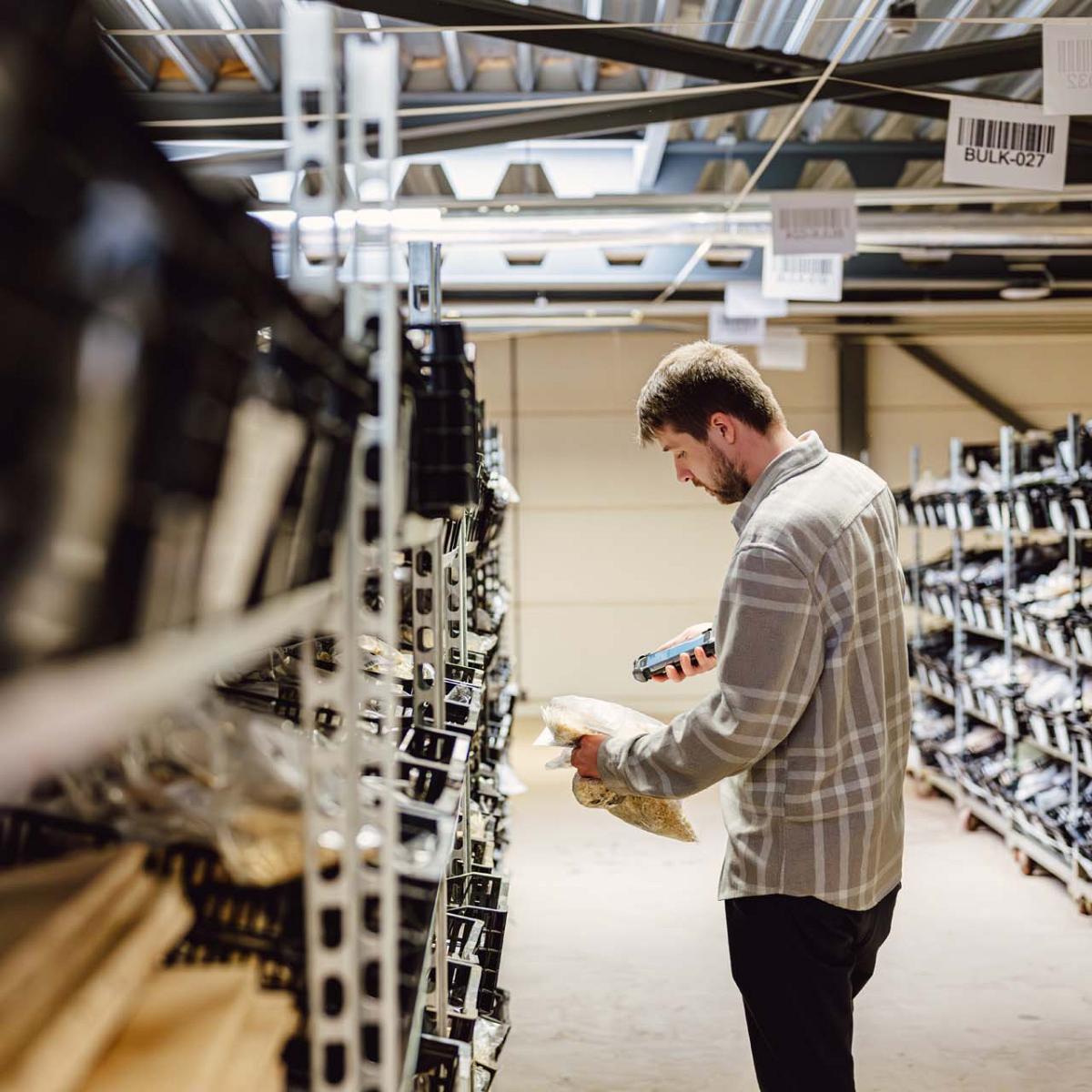 Man scant zakje bloembollen met handscanner.