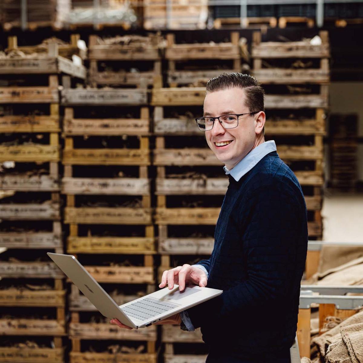 Smart Bulb consultant met laptop in handen voor kratten met bollen.