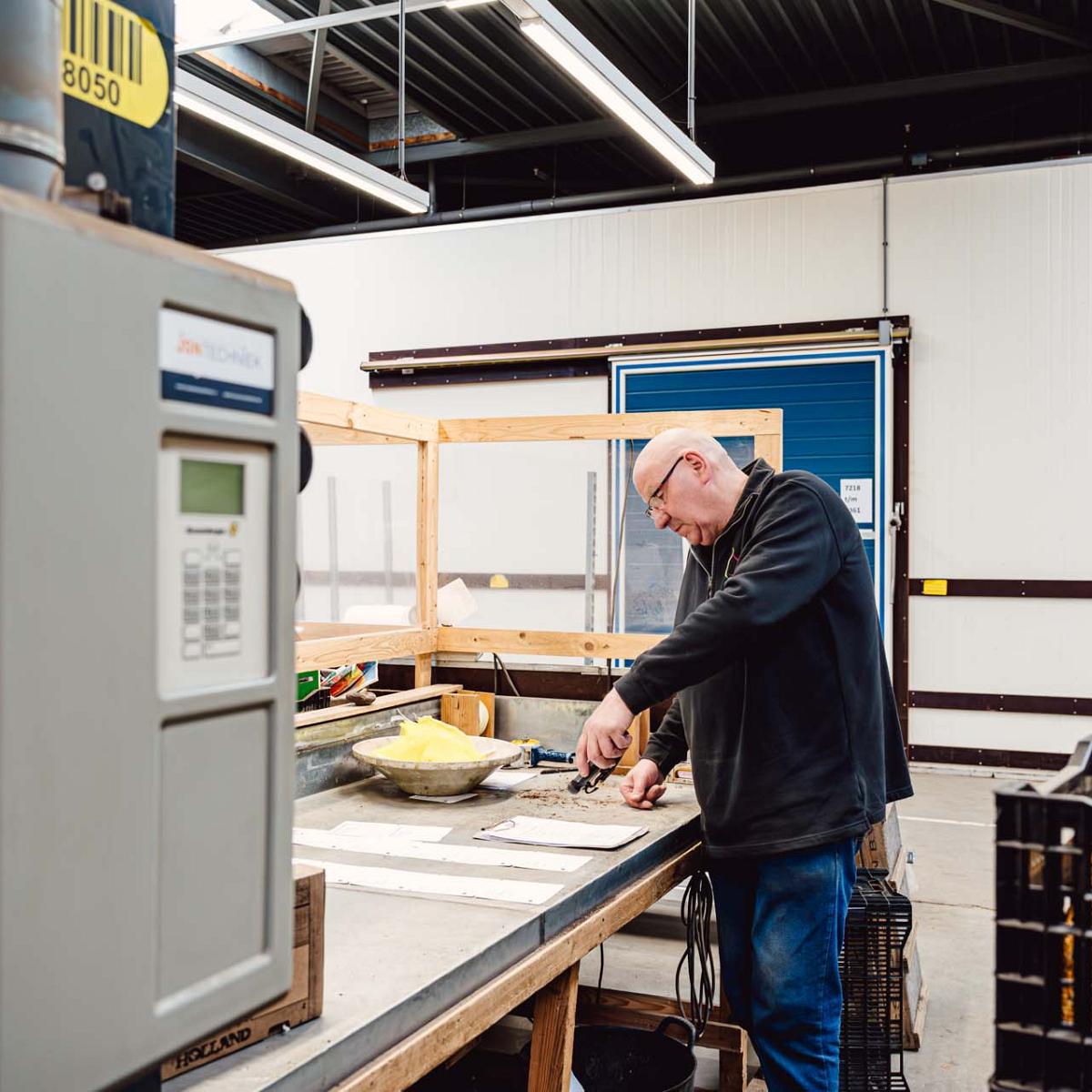 Man scant keurlijsten aan een werktafel.