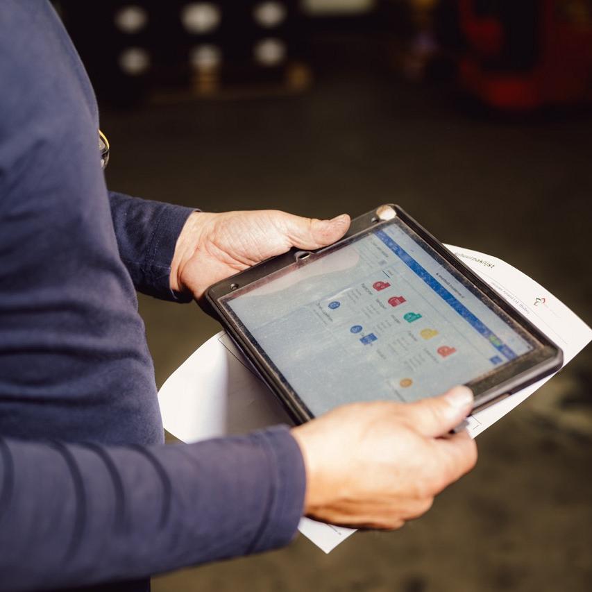 Persoon in blauwe trui houdt tablet vast met daarop Smart Bulb software, en heeft onder de tablet een stuk papier vast.